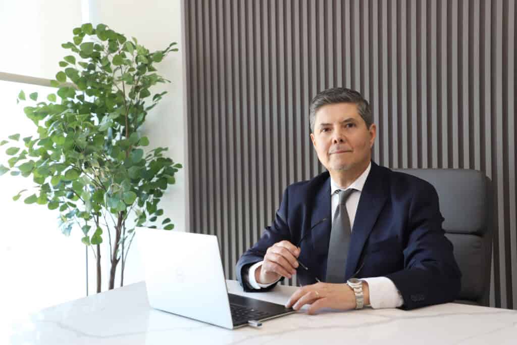 Business professional in formal attire sitting at a desk with a laptop, representing the expert team at Renovo Health and Beauty.