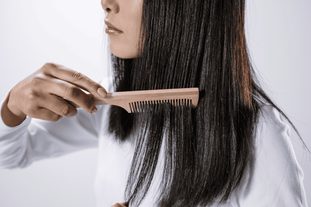 Woman brushing shiny, healthy hair, promoting hair regeneration and advanced cell therapy treatments for hair loss at Renovo Health and Beauty.