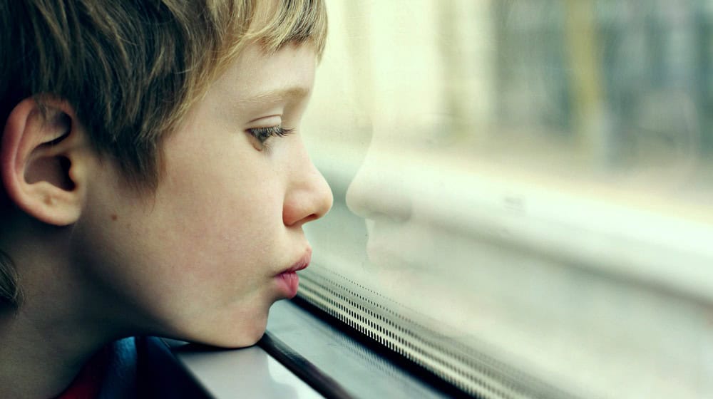 Child looking out the window, seeking hope for autism treatment in Mexico.
