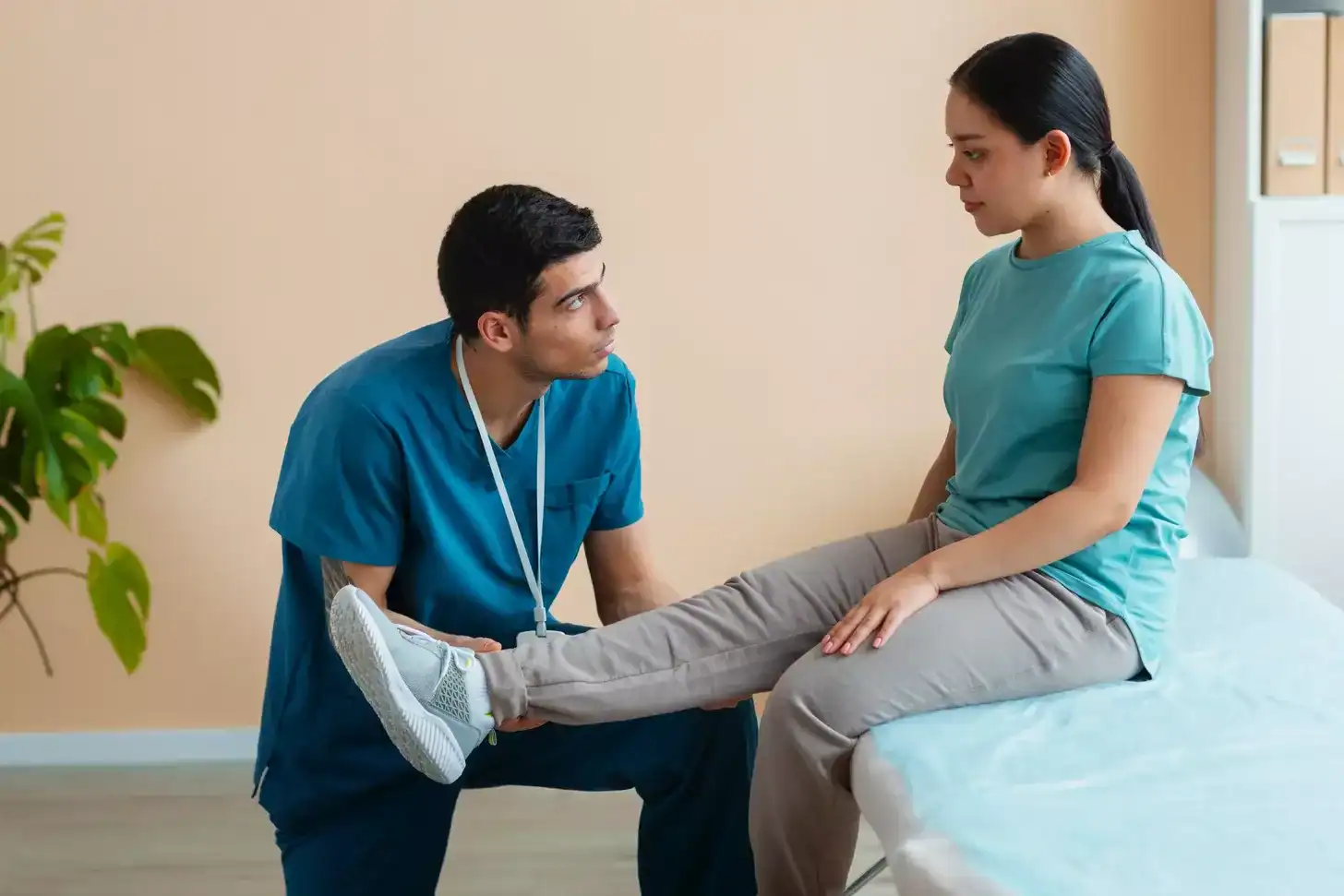 Healthcare professional assisting a patient with leg therapy in a clinical setting, promoting health and wellness services at Renovo Health and Beauty.
