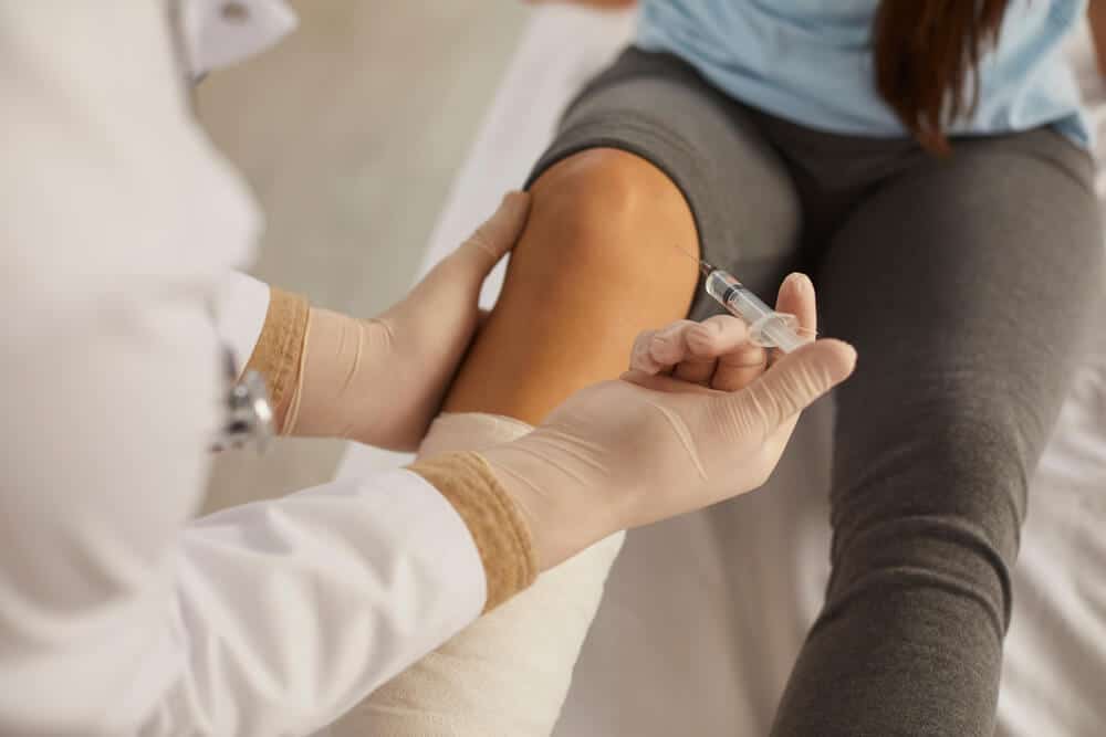 Medical professional administering a knee injection to a patient for pain relief or treatment at Renovo Health and Beauty in Tijuana.